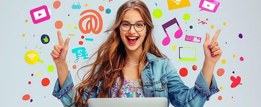 Persona sonriendo frente a una computadora personal y señalando diversas caricaturas que la rodean y refieren a música, video y otros contenidos en herramientas de marketing digital