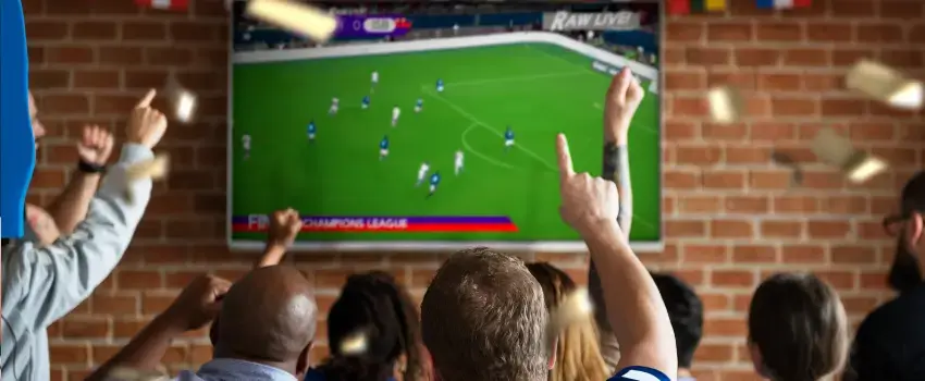 Grupo de aficionados celebrando frente a una pantalla, ejemplificando cómo los anuncios mundial de fútbol capitalizan la emoción colectiva. 