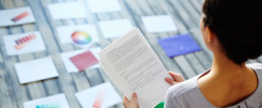 Persona revisando una guia de estilo de marca frente a una serie de diapositivas con colorimetría y otros elementos que la integran