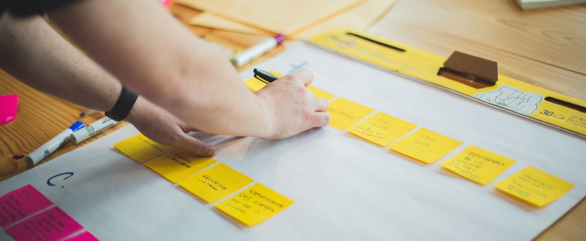 Persona midiendo un plano en una mesa para realizar una planeación anual exitosa en su empresa.
