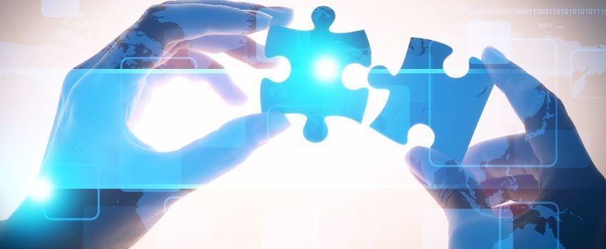 Manos embonando dos piezas de rompecabezas, asimilando la integración de datos como un proceso exitoso