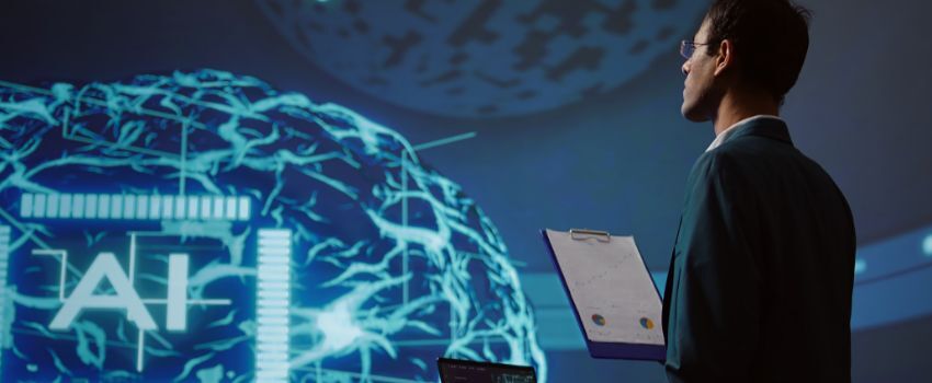Persona con computadora personal frente a la proyección de un cerebro virtual, con las letras IA en el centro